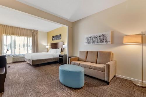 a hotel room with a bed and a couch and a chair at Sleep Inn & Suites in Wisconsin Rapids