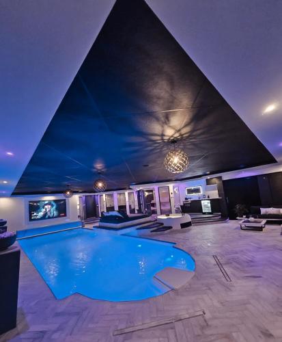 a large swimming pool in a room with a pyramid ceiling at Bed & Wellness Malina Deluxe zwembad suite in Lelystad
