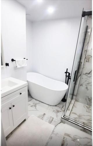 a white bathroom with a tub and a shower at Cute 2 BDR condo in Montréal