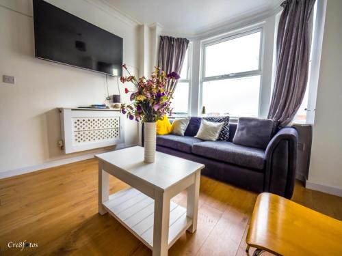 a living room with a couch and a table with flowers at En-suite 4 Woodhouse, private bath, 2 kitchen in Stoke on Trent