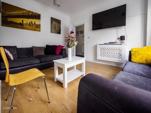 a living room with a couch and a table with flowers at En-suite 4 Woodhouse, private bath, 2 kitchen in Stoke on Trent