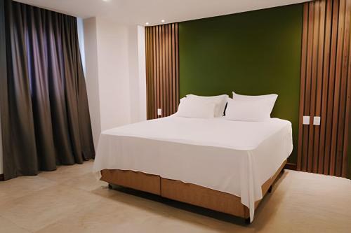 ein Schlafzimmer mit einem großen weißen Bett und einer grünen Wand in der Unterkunft Waua BSM| 6 suítes, Piscina, hidro, sala de jogos, in Barra de São Miguel
