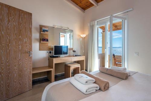 - une chambre avec un lit, un bureau et une télévision dans l'établissement Krouzeri Beach Apartments, à Nisakion