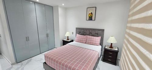 a bedroom with a pink bed and two lamps at Apartamento Turistico Torre del molino in Bogotá