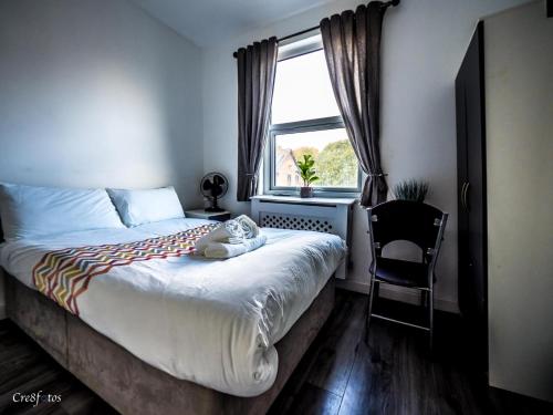 1 dormitorio con 1 cama con silla y ventana en En-suite 5 Woodhouse, private bath, 2 kitchen, en Stoke on Trent