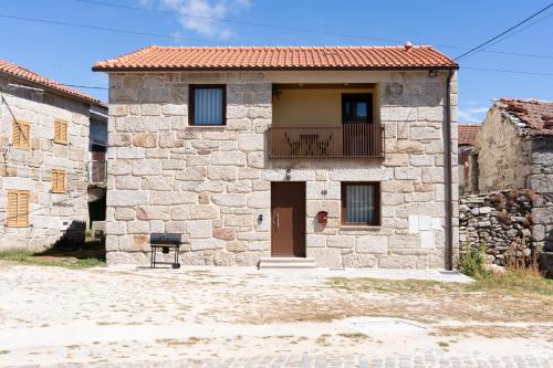 a stone house with a balcony and a chair outside at Casa Flavius Montalegre in Montalegre