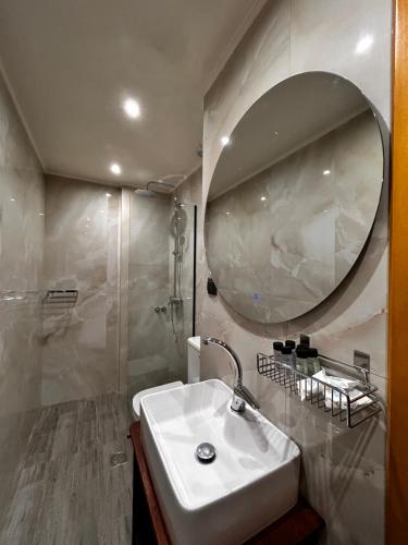 a white bathroom with a sink and a mirror at MetsoVillas στο κέντρο του Μετσόβου in Metsovo