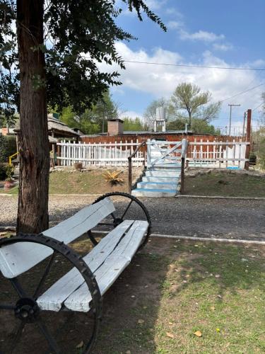 un banc blanc situé à côté d'un arbre dans l'établissement Cabañas La Lila, à Santa Rosa de Calamuchita