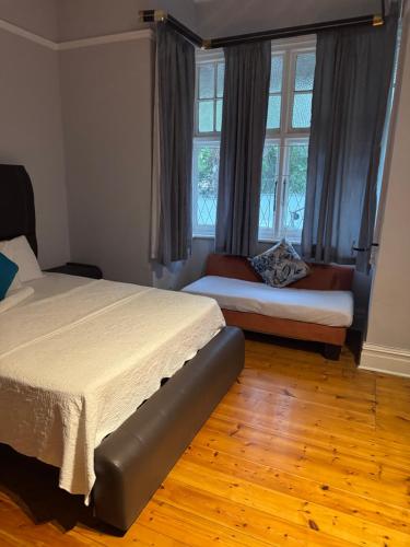 a bedroom with two beds and a couch and windows at Eagles Enest BnB in Pietermaritzburg