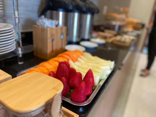 Una bandeja de comida con fresas y queso en un mostrador. en Keko Hotel, en Guapiaçu