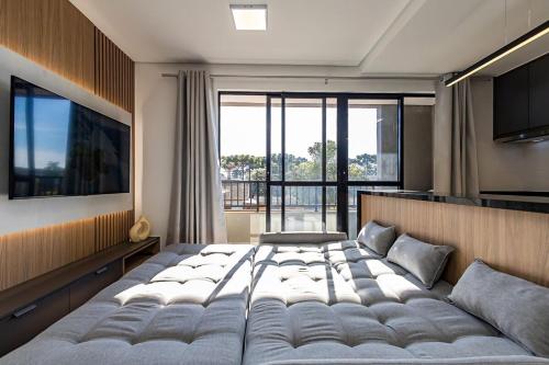 une chambre avec un grand lit et une grande fenêtre dans l'établissement Edificio Heart Urban Habitat, à Curitiba