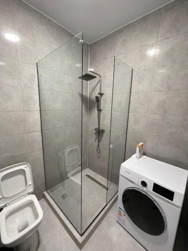 a bathroom with a shower and a washing machine at NBG Aparthotel in Batumi