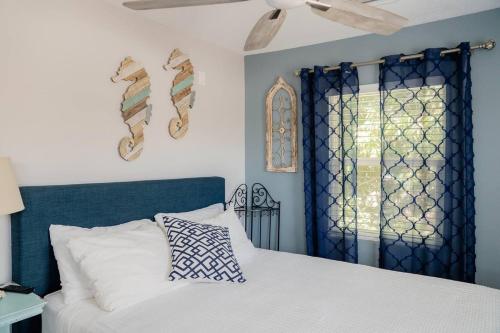 a bedroom with a bed with a blue headboard and a window at Cozy Coastal Cottages of Dunedin 4 in Dunedin