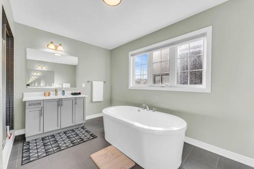 a white bathroom with a tub and a window at Luxury Mansion with Chefs Kitchen by Niagara Falls in Thorold