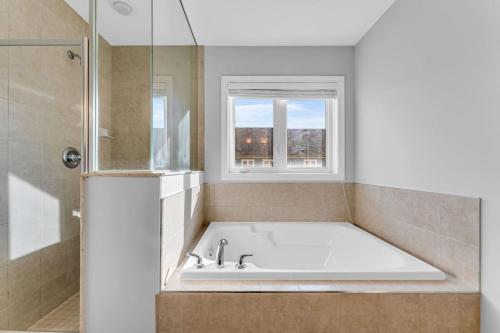 a white bath tub in a bathroom with a window at Cozy Home in Niagara 10 mins from Falls and Brock in Thorold