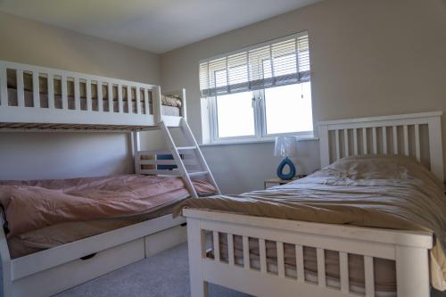 a bedroom with two bunk beds and a window at Ardlui House Gardens in High Blantyre