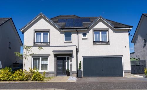 a white house with solar panels on the roof at Ardlui House Gardens in High Blantyre