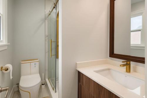 Un baño con inodoro, lavabo y espejo. en Spacious 6BR Getaway Sleeps 16 Yard and Parking, en Brampton