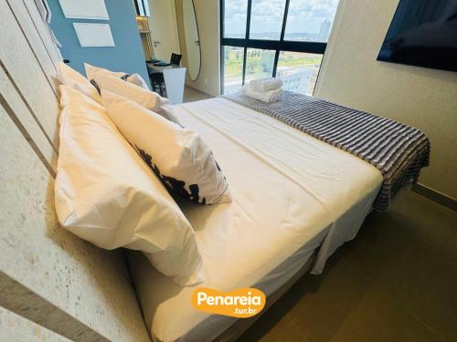 a bed with white sheets and pillows in a room at Emunah Di Città Flats Ponta de Campina in Cabedelo