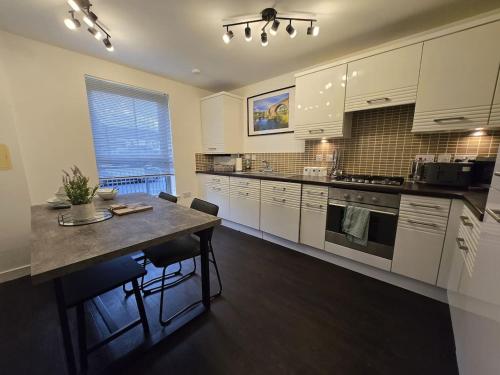 een keuken met witte kasten en een tafel met stoelen bij Modern Stirling Apartment - Free Parking in Stirling