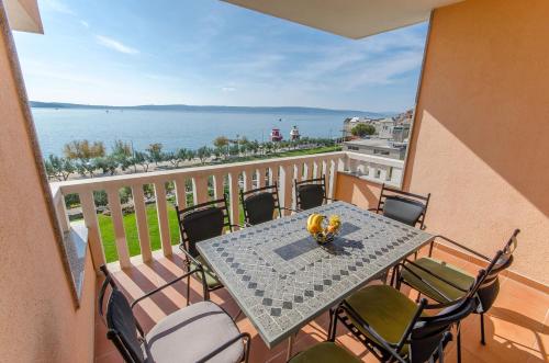 ein Tisch und Stühle auf einem Balkon mit Blick auf das Wasser in der Unterkunft Apartment Luxury Cream in Kaštela