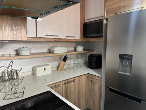 eine Küche mit Holzschränken und einem Edelstahlkühlschrank in der Unterkunft Davenport Durban in Durban