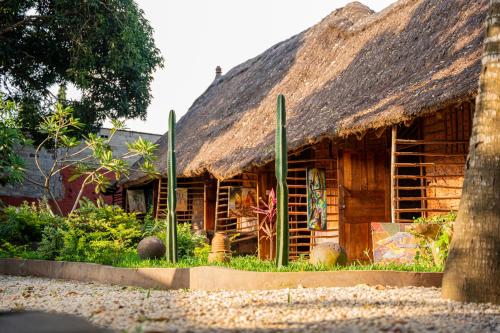 a wooden house with a thatched roof at Le Jardin Secret in Ouidah