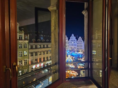 a window with a view of a city at night at Majestic Residence -150m2 with Iconic Market Square View AS HOME Apartamenty R506 in Wrocław