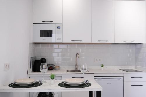 una cucina bianca con mobili bianchi e bicchieri da vino di La Zarzamora a Jerez de la Frontera