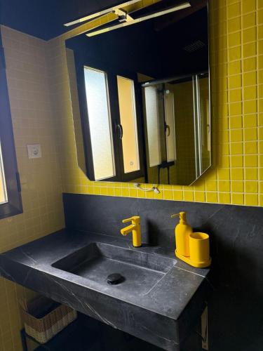 a bathroom with a sink with a mirror and yellow tiles at Los Royares in Candeleda