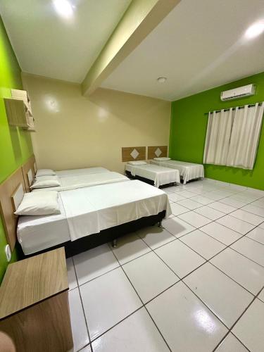 two beds in a room with green walls at Hotel Império Santarém in Santarém