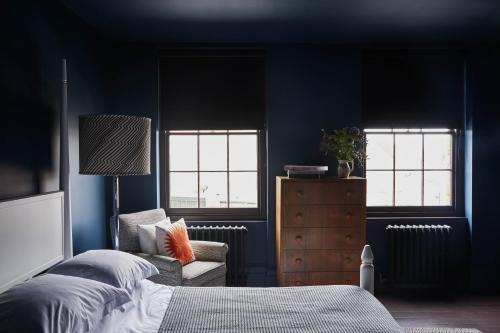 a bedroom with blue walls and a bed and a chair at Smiths Townhouse in Broadstairs