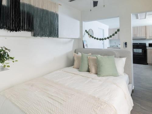 ein Schlafzimmer mit einem weißen Bett mit grünen Kissen in der Unterkunft AQUA Terrazas 2&3 2-Studio Beach Suite w Pool in Higuillar