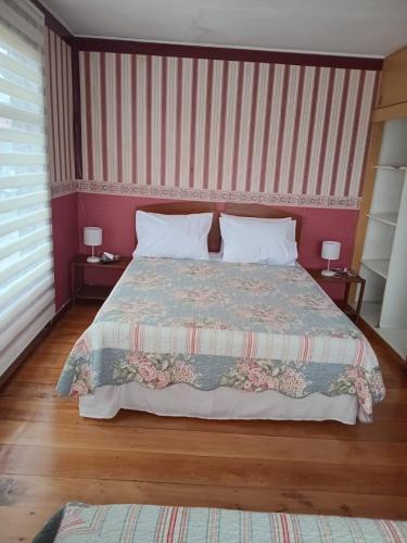 Un dormitorio con una cama grande con dos mesitas de noche. en Hostal Punto Austral, en Puerto Montt