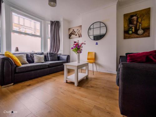 a living room with a couch and a table with flowers at En-suite 6 Woodhouse, private bath, 2 kitchen in Stoke on Trent