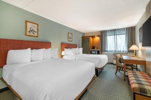 a hotel room with two beds and a desk at The Clocktower Hotel, an Ascend Collection Hotel in Cohoes
