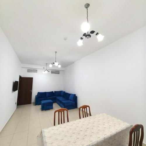 a dining room with a table and a blue couch at Family-Friendly, Near to Beach, Near Shops & Parks, City View in Ajman