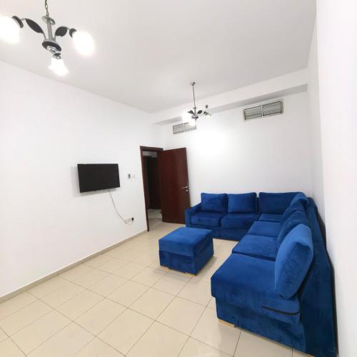 a living room with a blue couch and a tv at Family-Friendly, Near to Beach, Near Shops & Parks, City View in Ajman