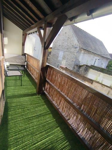 a balcony with green grass and a wooden fence at Le Perchoir de Linas, filet suspendu, appartement cosy in Linas