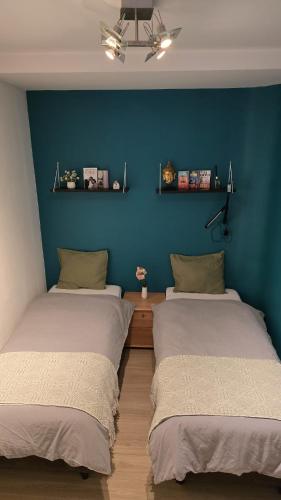 two beds in a room with a blue wall at Royal sleeping Brussels in Brussels