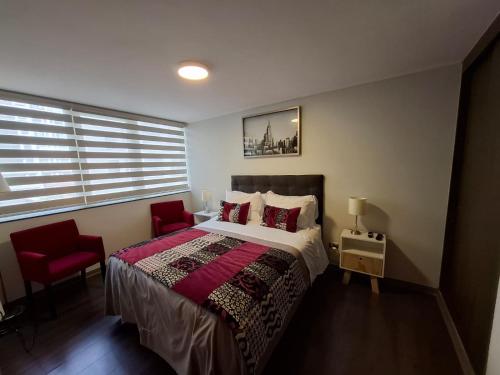 a bedroom with a bed and a red chair at Apart Lomas de San Andres CENTRO in Concepción