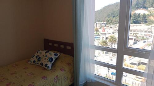 a bed with a pillow next to a window at departamentoplaya in Tomé