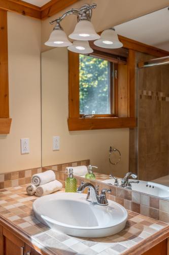 a bathroom with a sink and a mirror at Private A-Frame Log Cabin near Tremblant With Hot tub Game Room in Labelle