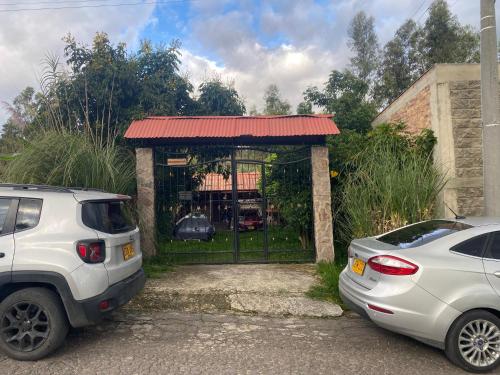two cars parked in front of a gate at Cabaña Emanuel in Paipa