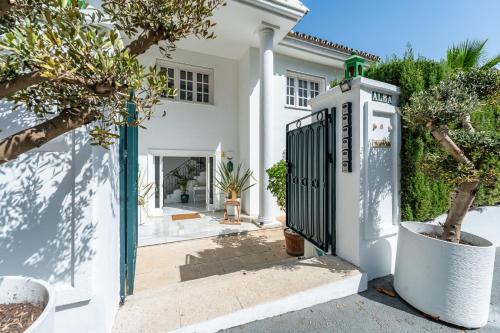 Biały dom z bramą i drzewami w obiekcie Aurora Boutique Hotel - Only Adults w Marbelli