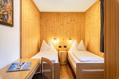 a small room with two beds and a desk at Villa Erina App C3 in Ortisei