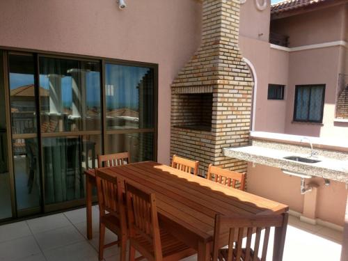 une table et des chaises en bois sur une terrasse avec une cheminée dans l'établissement Beverlly Hills, à Aquiraz