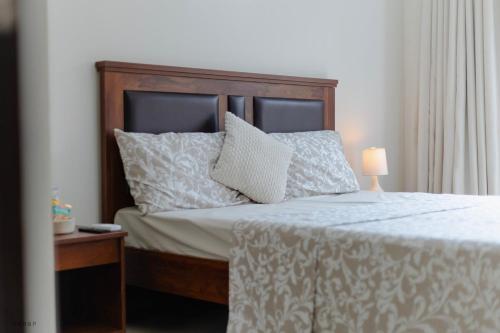 a bed with a wooden headboard and a lamp on a table at Modern 1BHK by Kastra Homes, Siolim in Cunchelim