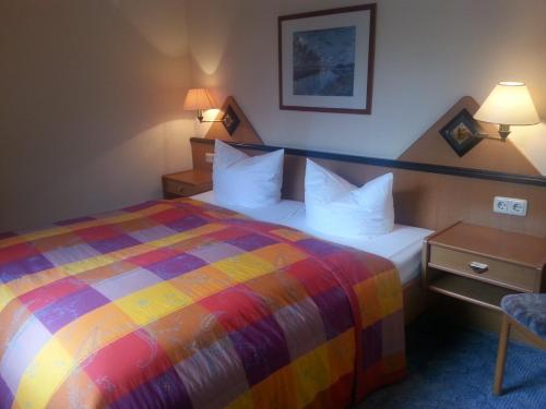 a hotel room with a colorful bed and a chair at Hotel und Restaurant Sackwitzer Mühle in Bad Schmiedeberg