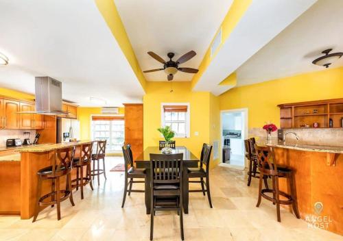 eine Küche und ein Esszimmer mit gelben Wänden, einem Tisch und Stühlen in der Unterkunft Breathtaking Chalk Sound Private Pool Sunset Villa in Providenciales